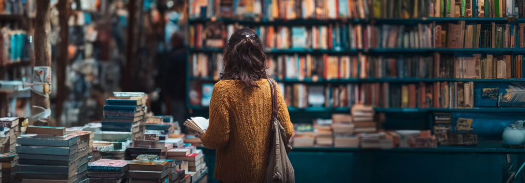 Cliente di libreria vista di spalle che sfoglia un libro pronta a sceglierne uno